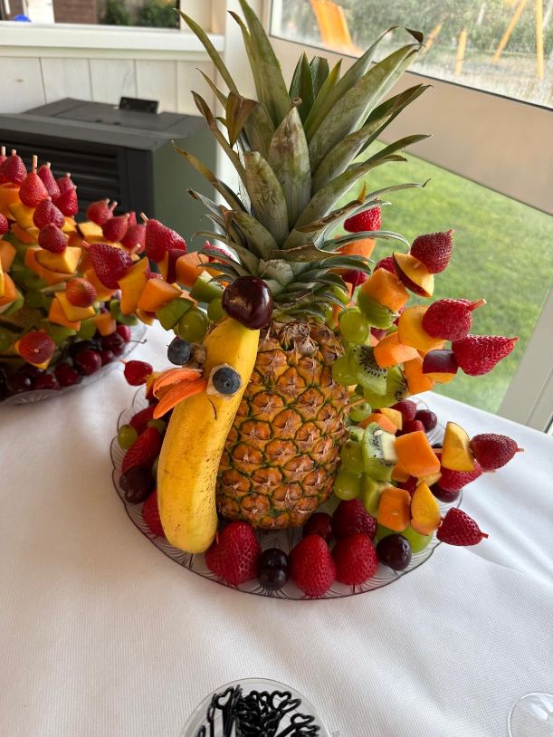Centrotavola artigianale di frutta fresca a forma di cigno, realizzato con ananas e frutti di bosco